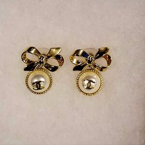 Chanel 25A gold-tone metal bow stud earrings with a faux pearl drop. 